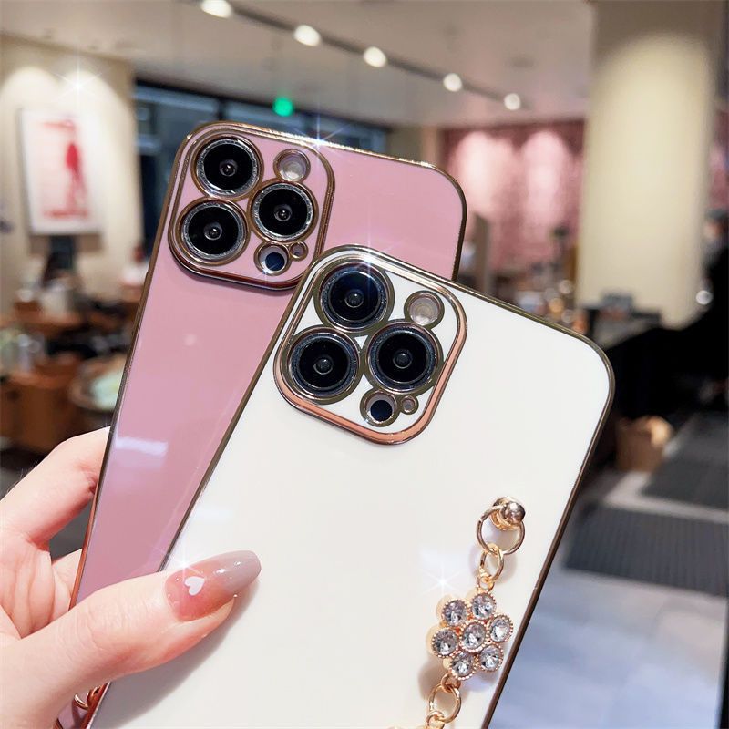 Pink and white phone cases; white case shows a blue rhinestone bracelet chain detail.