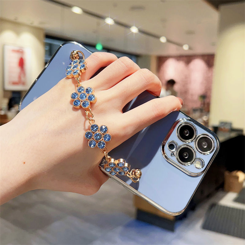 Light blue phone case with gold-toned edge and blue rhinestone bracelet wrapped charm.
