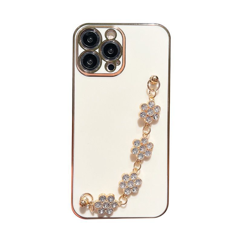 Cream phone case with gold-toned border and clear blue rhinestone bracelet charm.
