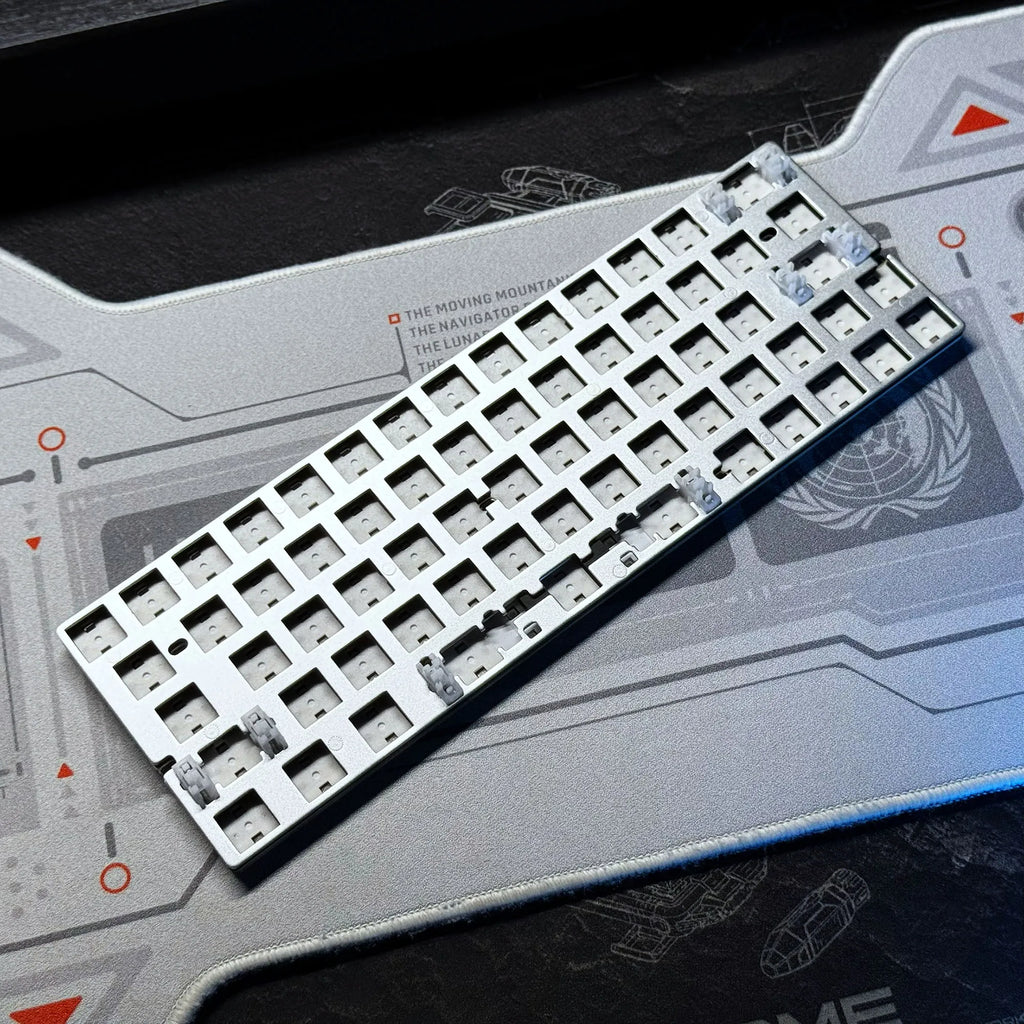 Keyboard PCB tray with white switch sockets and small silver components, angled view