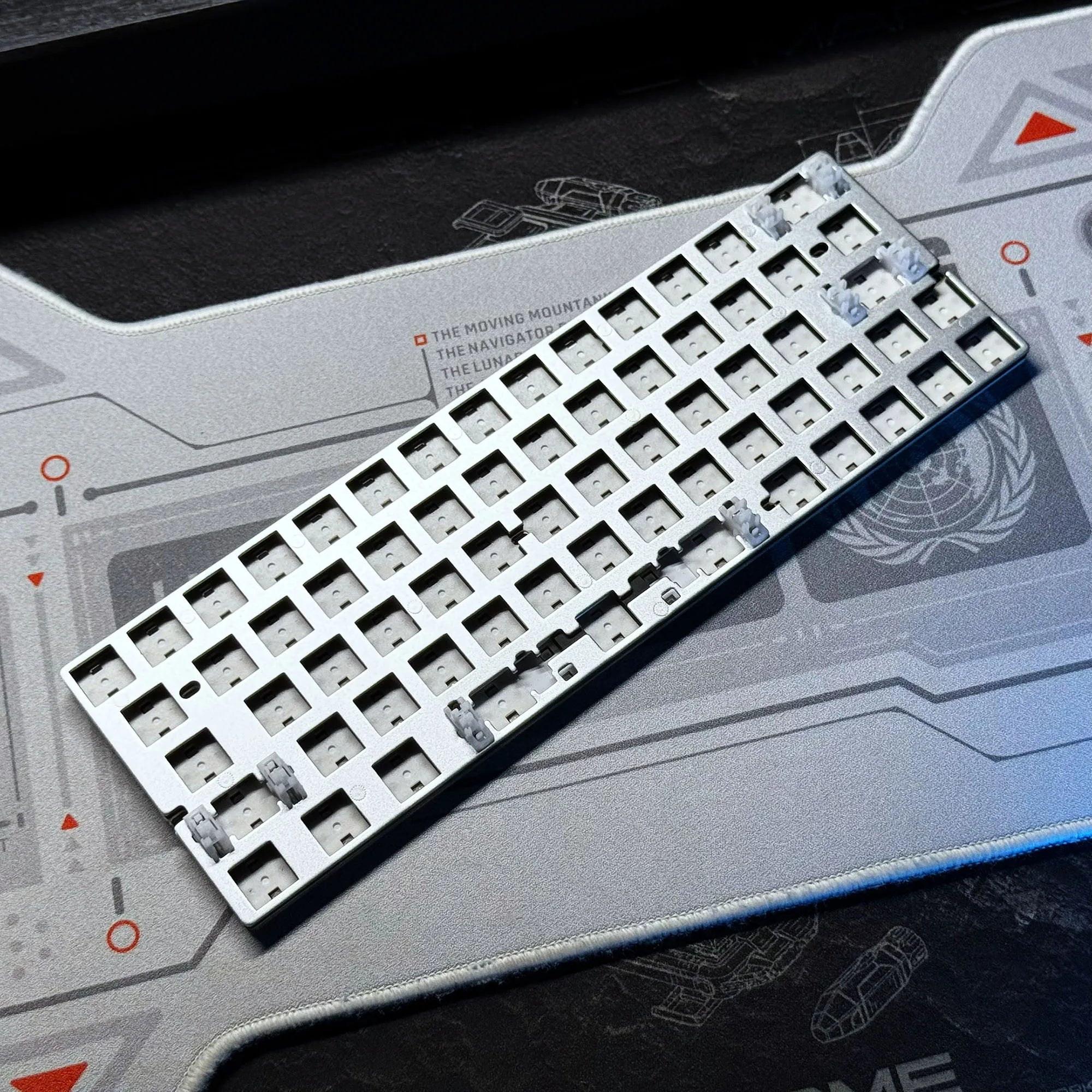 Keyboard PCB tray with white switch sockets and small silver components, angled view