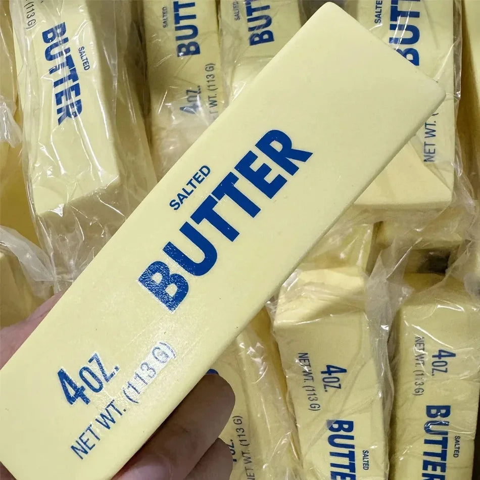 Yellow butter-stick squishy toy close-up, blue BUTTER and 4oz 113g text