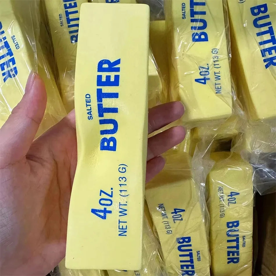 Yellow butter-stick squishy fidget toy held in palm, 4oz 113g salted BUTTER label