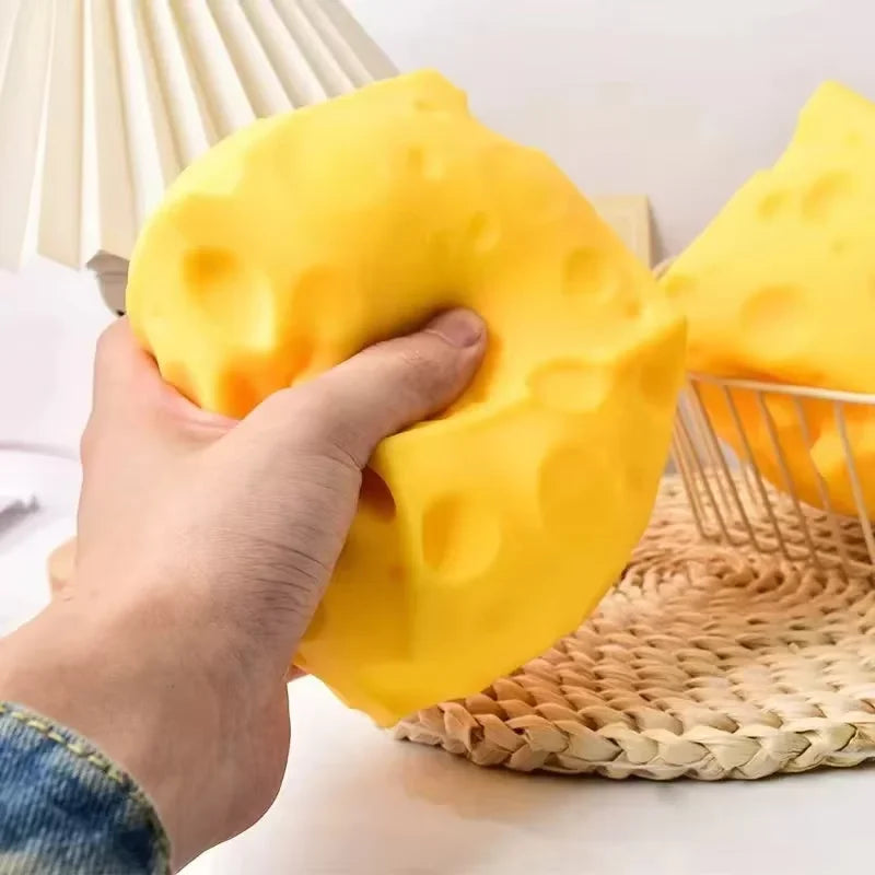 Large yellow cheese-shaped squishy toy with round holes, hand squeezing