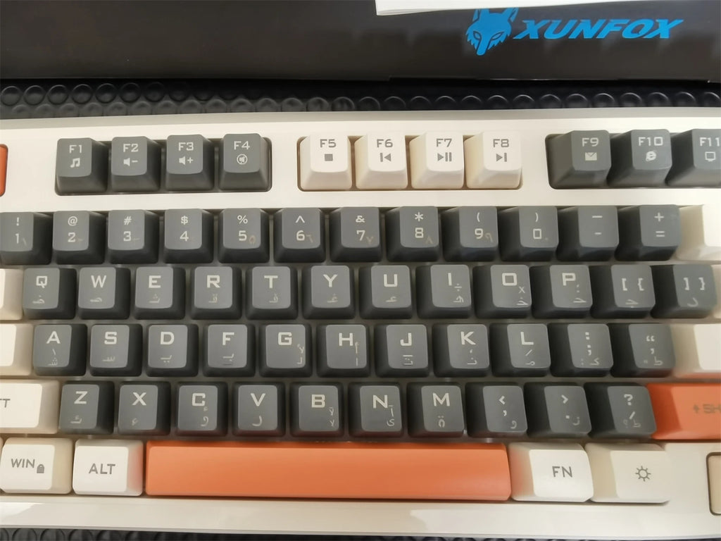 Close-up of keyboard keys with dark and cream legends and an orange spacebar
