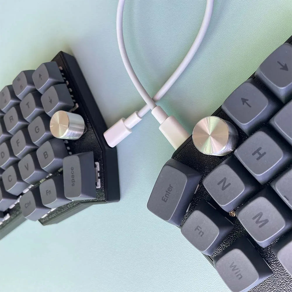 Close-up of Corne 4x6 split keyboard: dark keycaps, rotary knob, connected cable