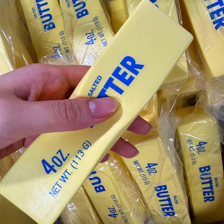 Yellow butter-stick squishy toy held in hand, salted BUTTER logo and 4oz 113g