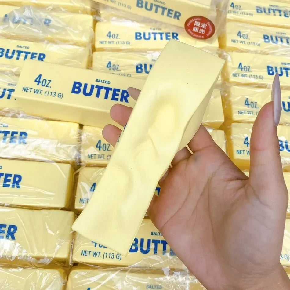 Yellow butter-stick squishy toy in hand, blue BUTTER and 4oz 113g text