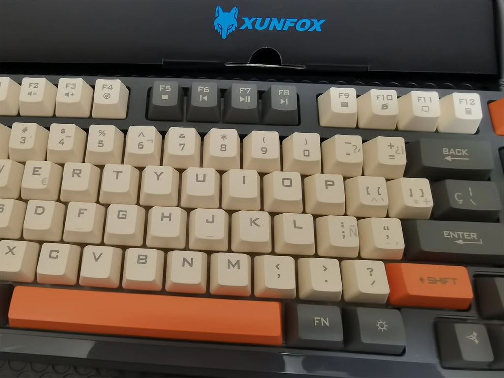 Close-up of cream and black keycaps with orange accent keys, RGB backlit keyboard