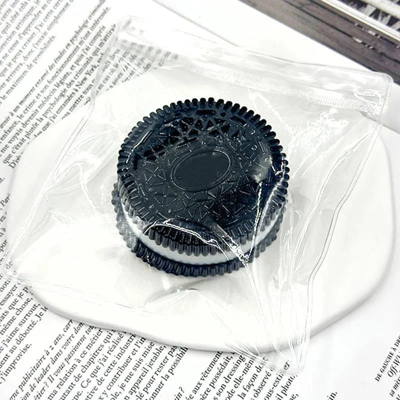 Black circular squishy stress relief toy with embossed center design, in a clear wrapper.