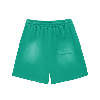 Green cotton shorts with elastic waistband, drawstring, back pocket, raw hem, sun-fade.
